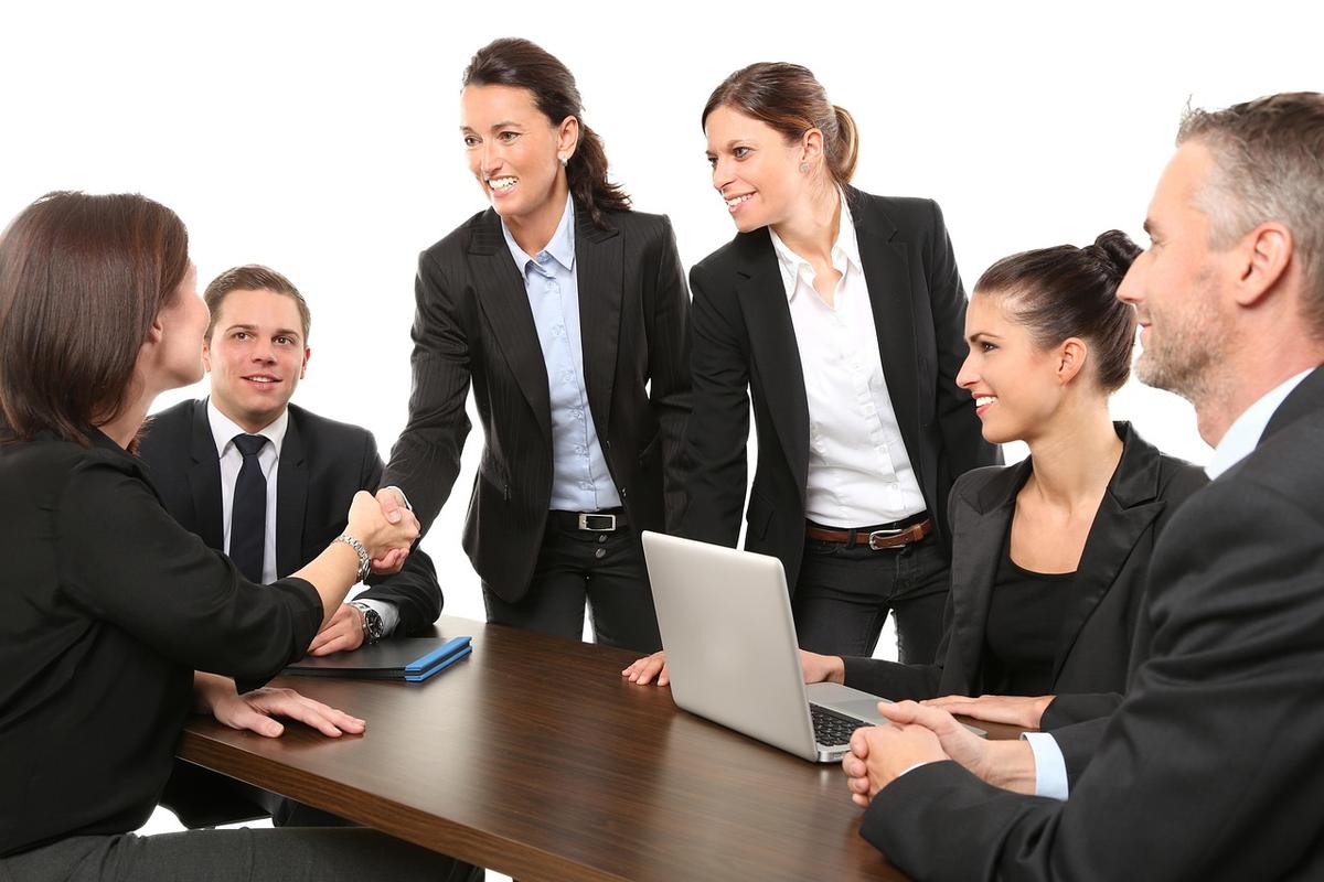 Équipe de professionnels réunis autour d'une table, l'un utilisant un ordinateur portable Équipe de professionnels réunis autour d'une table, l'un utilisant un ordinateur portable