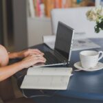 Une femme travaille à distance, utilisant ordinateur, cahier et café