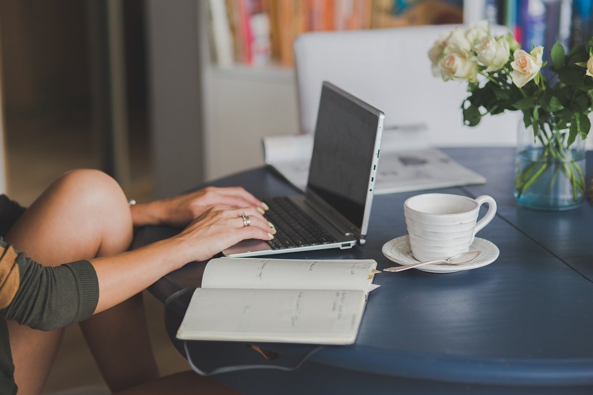 Une femme travaille à distance, utilisant ordinateur, cahier et café
